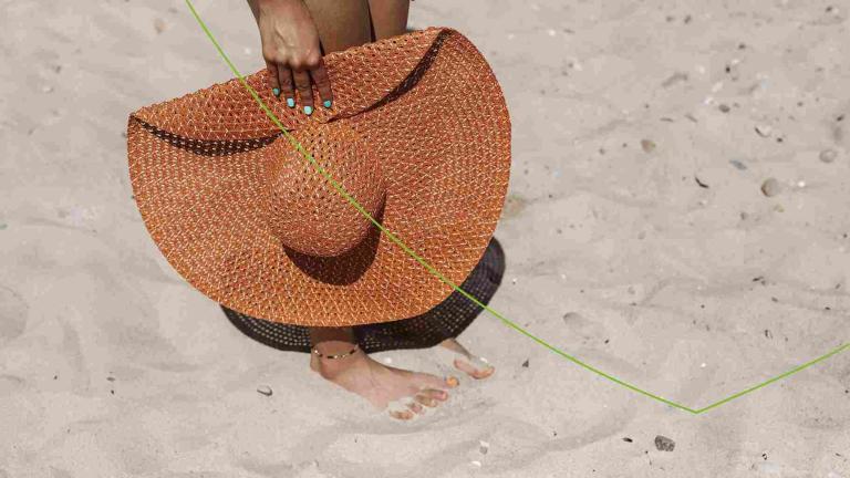 Vrouw op strand met hoed in de hand